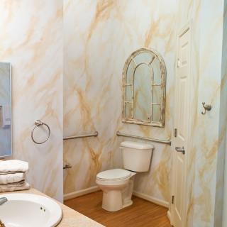 A stylish bathroom with a marble-patterned wall, equipped with a toilet, sink, and mirror.