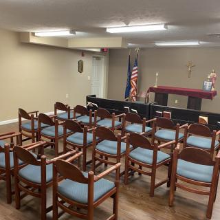 A small chapel with wooden chairs and an altar in the background.