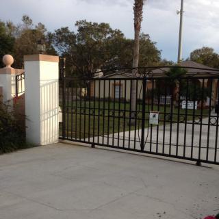 A residential driveway with a black metal gate and view of the garden.