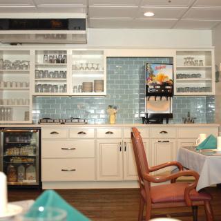 A cozy kitchen and dining area with neatly arranged cabinets, a beverage dispenser, and a table set for dining.