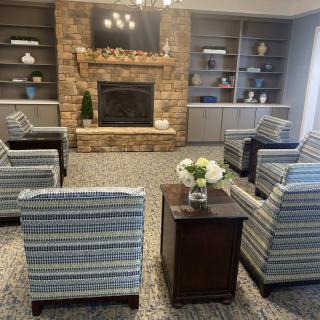 A cozy living room with striped armchairs arranged around a stone fireplace and flanked by built-in bookshelves.