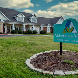 A building with a sign reading 'Memory Care' situated on a well-maintained lawn under a cloudy sky.