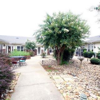 A serene courtyard featuring a paved walkway, lush greenery, and stone landscaping.