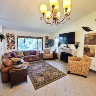 A cozy living room with a comfortable sofa, chairs, and a coffee table arranged around a fireplace and television.