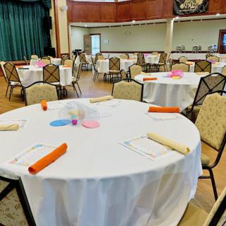 A spacious event venue set up with elegantly arranged tables and chairs, ready for a gathering.