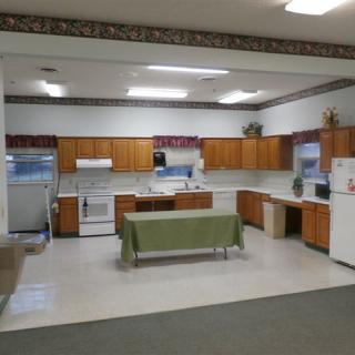 A spacious kitchen interior with wood cabinets, appliances, and a central table.