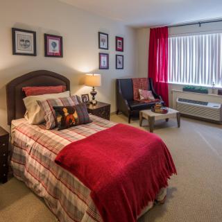 A cozy bedroom with a neatly made bed, colorful bedspread, and matching decor.