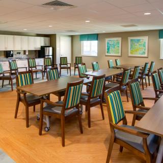 A well-arranged dining area with multiple tables and chairs, adjacent to a kitchen space.