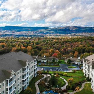 A scenic aerial view of a resort nestled amidst autumnal foliage with mountains in the background.