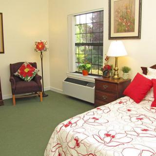 A cozy bedroom with a floral theme, featuring a neatly made bed, a comfortable chair, and tasteful decor.