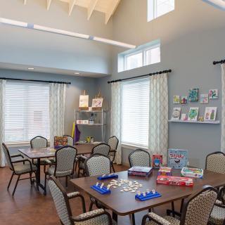 A community room with tables, chairs, and games set up for activities.