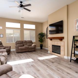 A spacious modern living room with comfortable sofas and a mounted TV above the fireplace.
