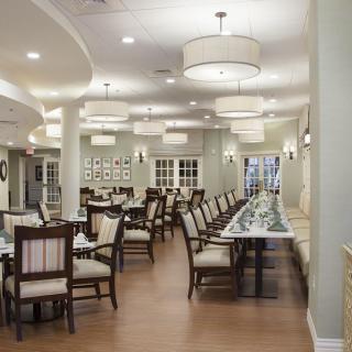 A well-lit dining room with neatly arranged tables and chairs.