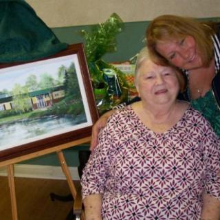 Two people posing happily with a framed painting.