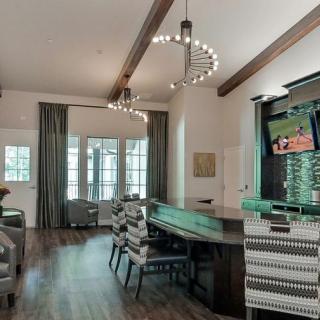 A modern living space featuring a bar counter, seating area, wooden beams, and elegant chandeliers.