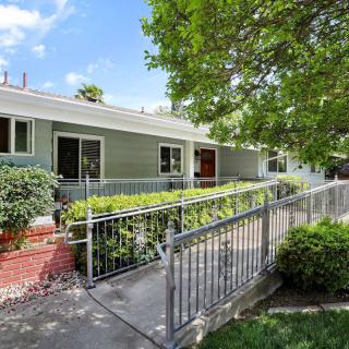 A charming house with a ramp and surrounded by lush greenery.