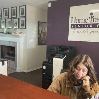 A receptionist at Home Instead Senior Care engaged in a phone conversation.