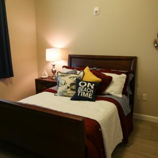 Cozy bedroom with neatly arranged pillows and a bedside lamp.