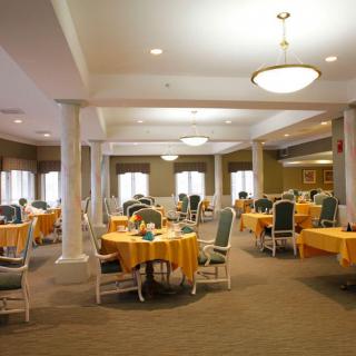 A spacious dining area with neatly arranged tables and chairs, featuring warm lighting and a cozy atmosphere.