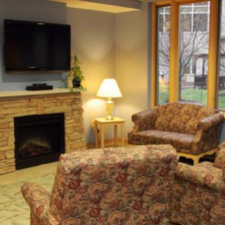 A cozy living room setup featuring comfortable seating, a warm fireplace, and natural light from large windows.