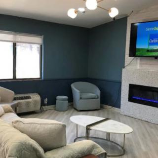 A modern living room with comfortable seating, a sleek fireplace, and a mounted television.