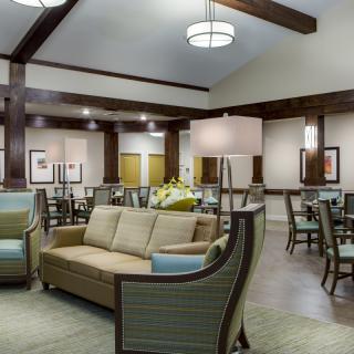 A spacious lounge area with comfortable seating and dining tables, featuring modern lighting and wooden beams.