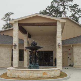 A large house with a prominent entrance featuring a decorative fountain.