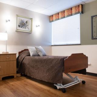 A well-lit hospital room featuring a bed, nightstand, and decorative artwork.