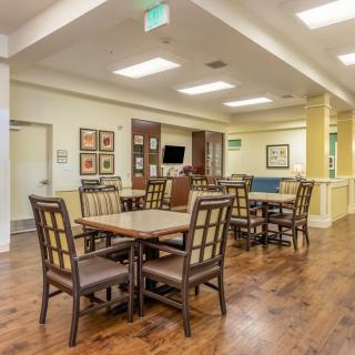 A well-lit dining area with multiple tables and chairs featuring a hardwood floor.