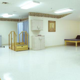 A spacious and well-lit rehabilitation room equipped with a ramp and minimal furnishings.