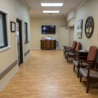 An empty waiting room with chairs lined up against the wall and a television mounted on the opposite side.