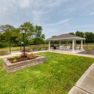 A charming outdoor pavilion surrounded by lush greenery and a well-maintained garden.