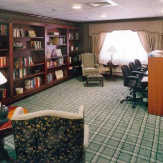 A cozy library room with bookshelves, seating, and a window providing natural light.