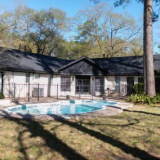 A cozy house with a swimming pool in the backyard, surrounded by trees.