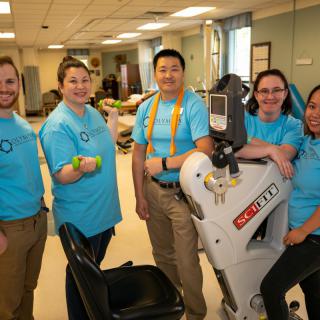 A team of healthcare professionals posing with a rehabilitation robot.