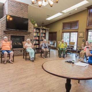 A group of seniors gathered in a comfortable seating area for a community meeting.
