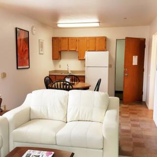 A cozy apartment living area with a white sofa, dining table, and a compact kitchen.