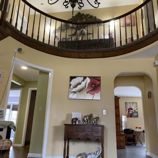 A spacious living room featuring a high ceiling with a chandelier, decorative art pieces, and elegant furniture.
