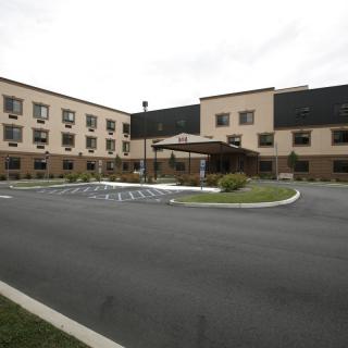 A modern hotel building with a parking lot and entrance area.