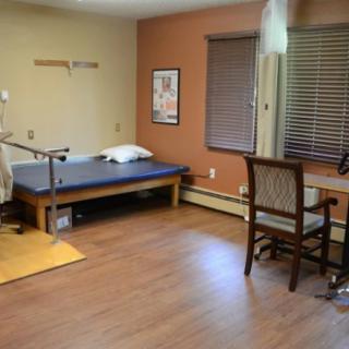 A therapy room equipped with a treatment table and exercise equipment for physical rehabilitation.