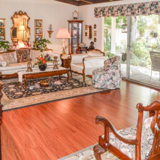 A traditional living room with elegant furnishings, featuring a hardwood floor, plush rug, and large sliding glass doors that provide natural light.