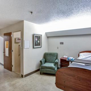 A clean and organized hospital room with a bed, chair, and minimal decorations.