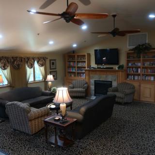 A cozy living room featuring multiple sofas, a fireplace, bookshelves, and a television.