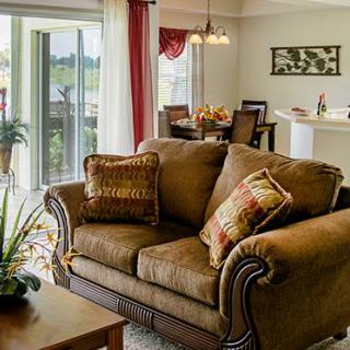 A cozy living room with a brown couch, decorative pillows, and an adjoining dining area.