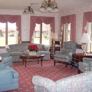 A vintage-style living room with floral-patterned sofas and armchairs, complemented by a coffee table and lamps.