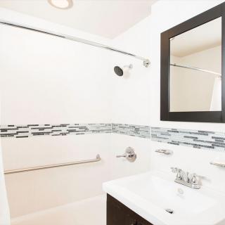 A modern bathroom featuring a sink, mirror, and tiled shower area.