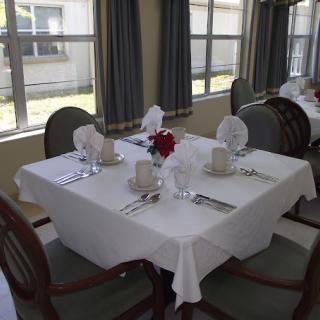 A neatly set dining table with a white tablecloth and elegant place settings in a well-lit restaurant.
