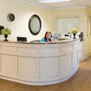 A reception area with a curved desk and a person working behind it.