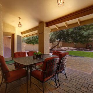 A cozy outdoor dining area showcasing a table with four cushioned chairs under a charming patio.