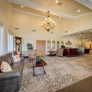 A spacious and elegantly decorated lobby with a chandelier, comfortable seating, and a reception desk.